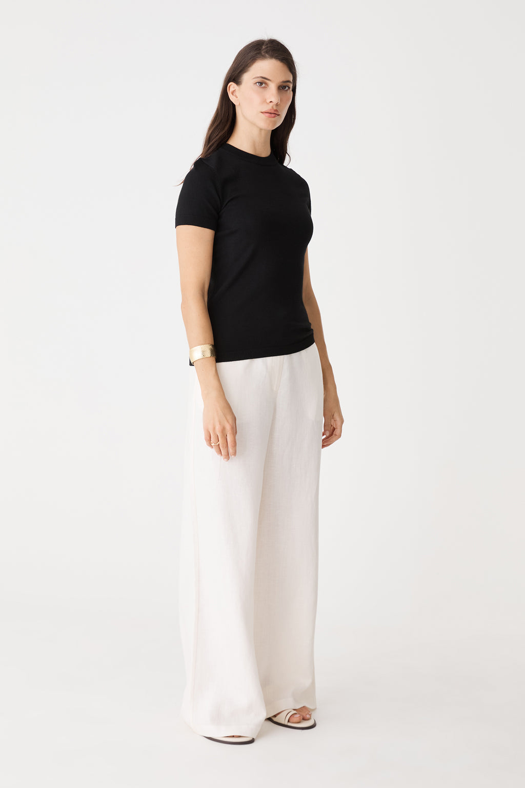 Side view of the black Catherine Short Sleeve Knit with white wide-leg pants