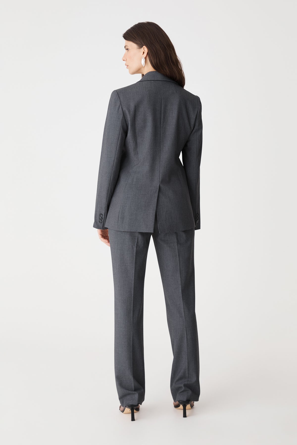 Back view of the dark grey blazer showing back vent, worn with matching pants