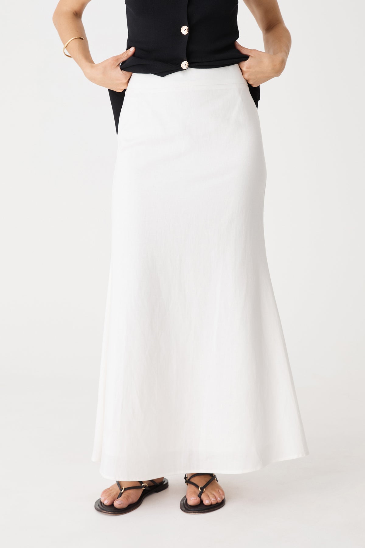 Close-up front view of the ivory maxi skirt's high waistband and flute hem
