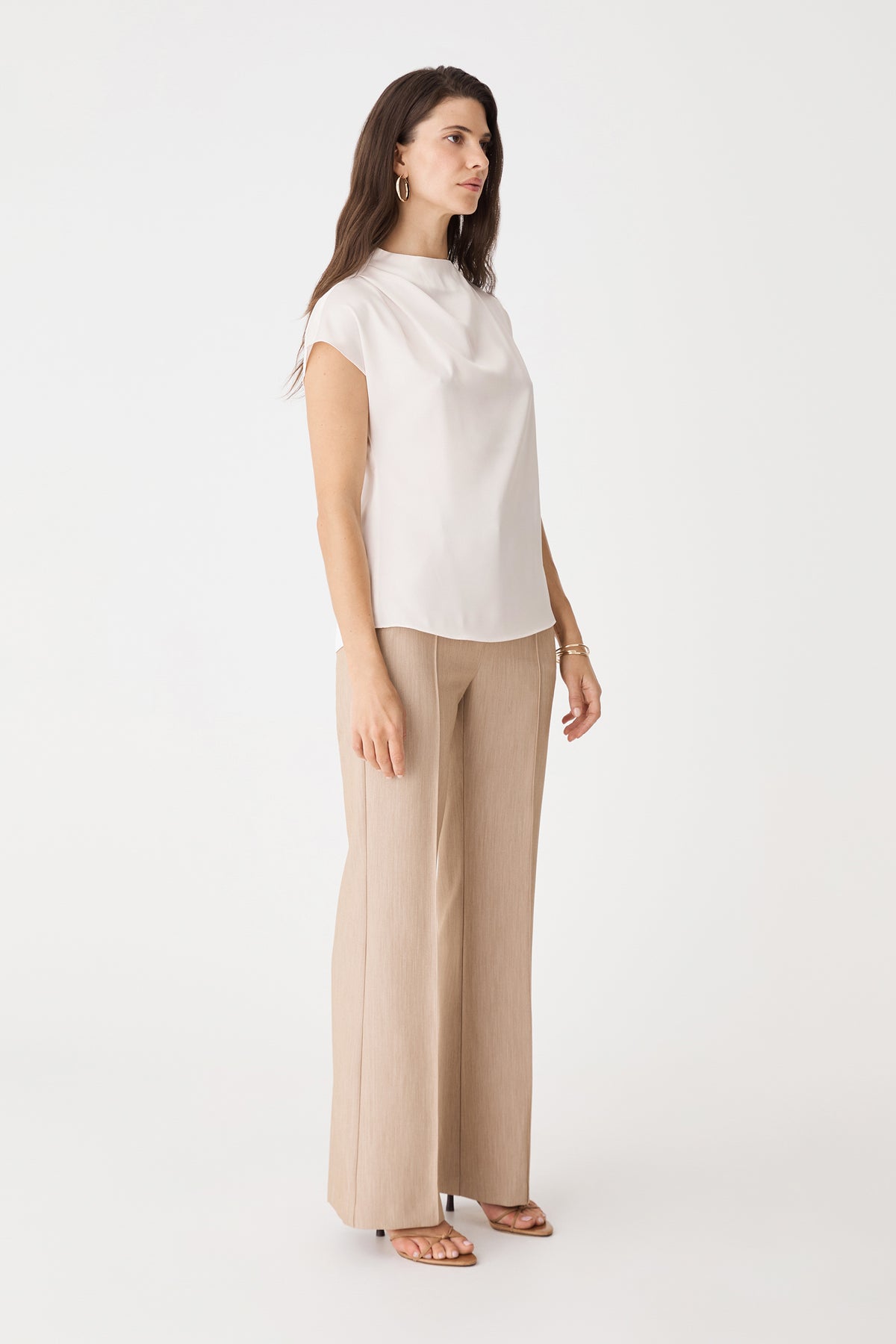 Side view of the pearl Zafina Pleated Draped Top with beige wide-leg trousers