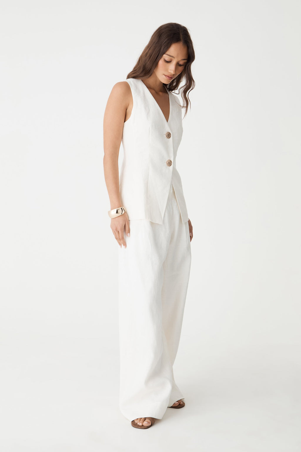 Side view of the white Ami V-Neck Linen Vest showing longline hem over wide leg pants