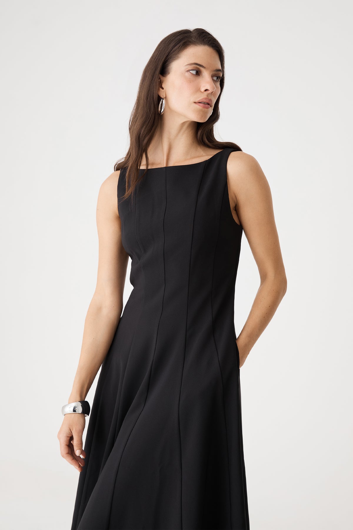 Close-up of the black dress bodice showing vertical panel seams and boat neckline