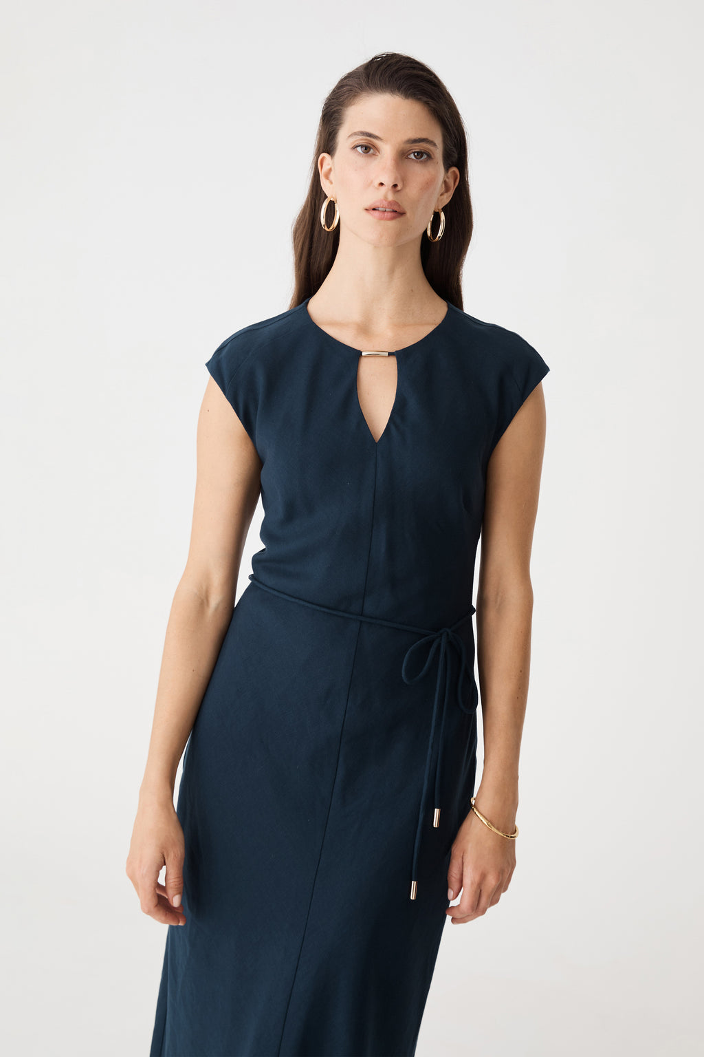 Close-up front view of the keyhole neckline and tie belt on the navy maxi dress