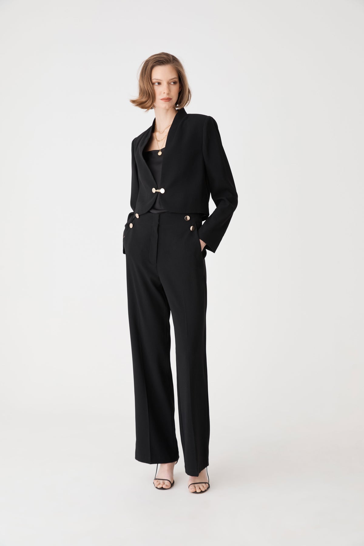 Full-length front view of the black cropped jacket worn open over matching black trousers