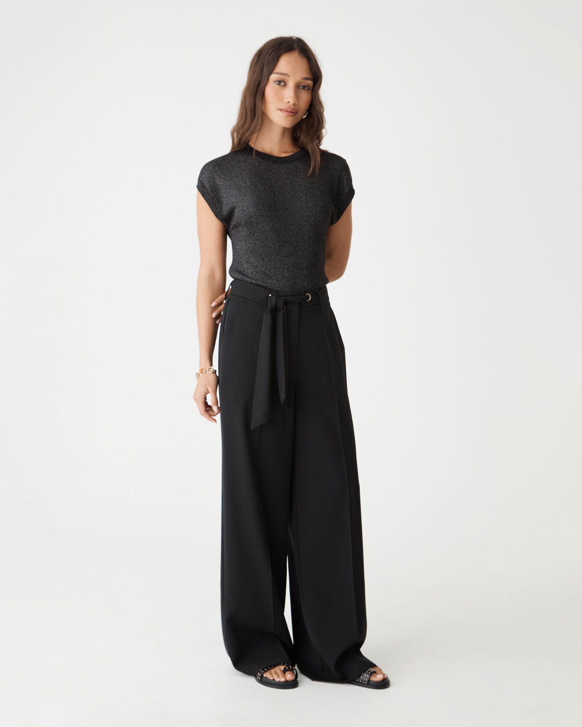 Side-front view of the black Saskia Lurex Knit Top with tie-waist black trousers