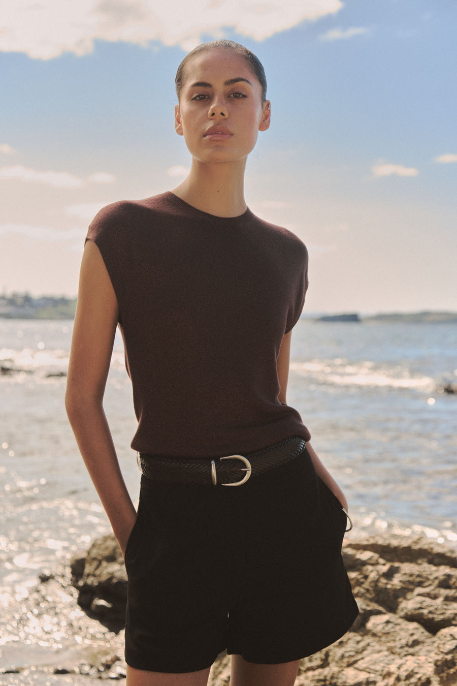 Saskia Lurex Knit Top in Fudge worn with black shorts and belt, outdoor coastal setting, front view