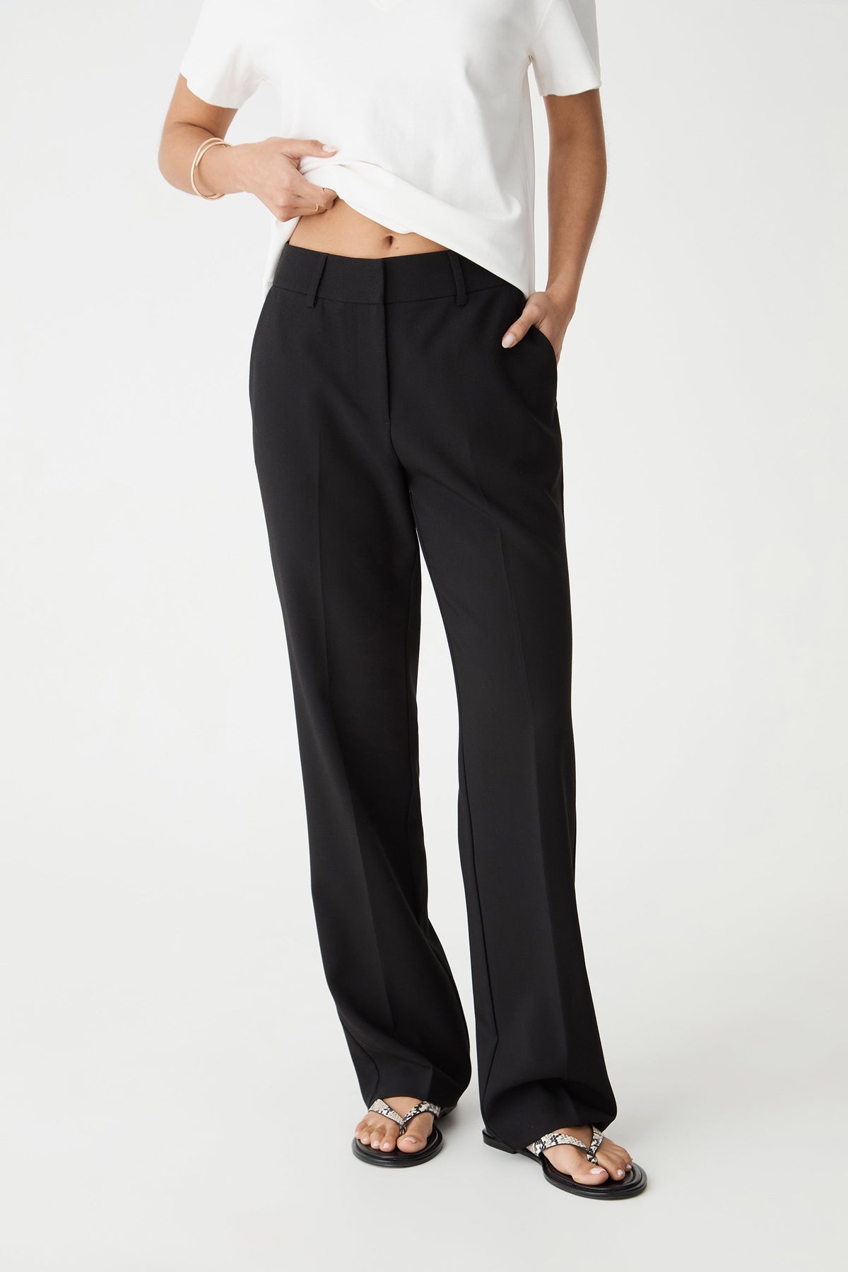 Close-up front view of the black Nikki pants showing waistband, fly zip and side pockets