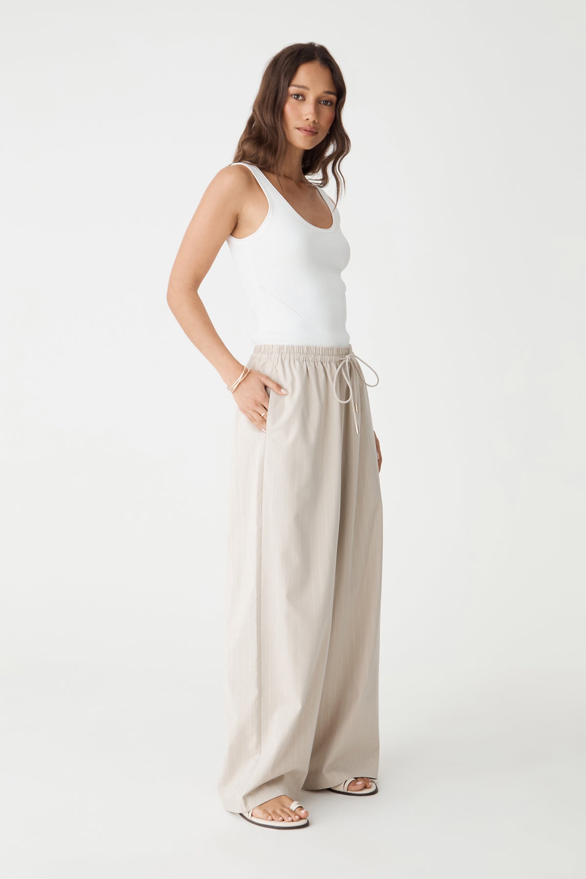 Side view of the beige pinstripe wide-leg pants