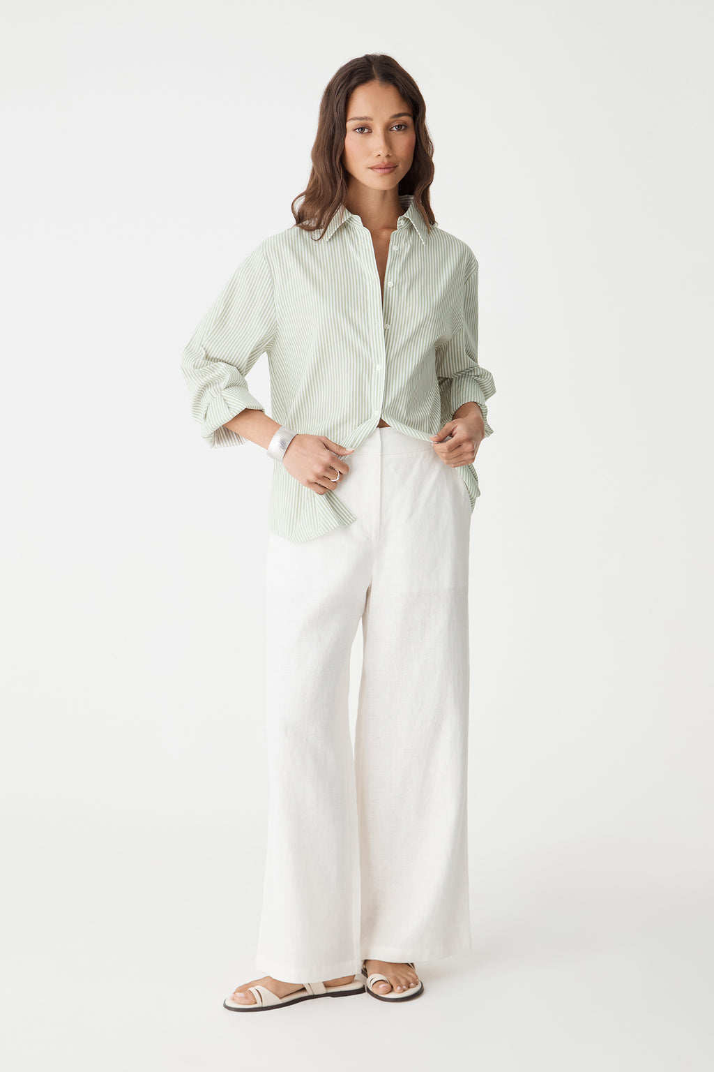 Front view of the green stripe shirt with sleeves pushed up, worn with white trousers