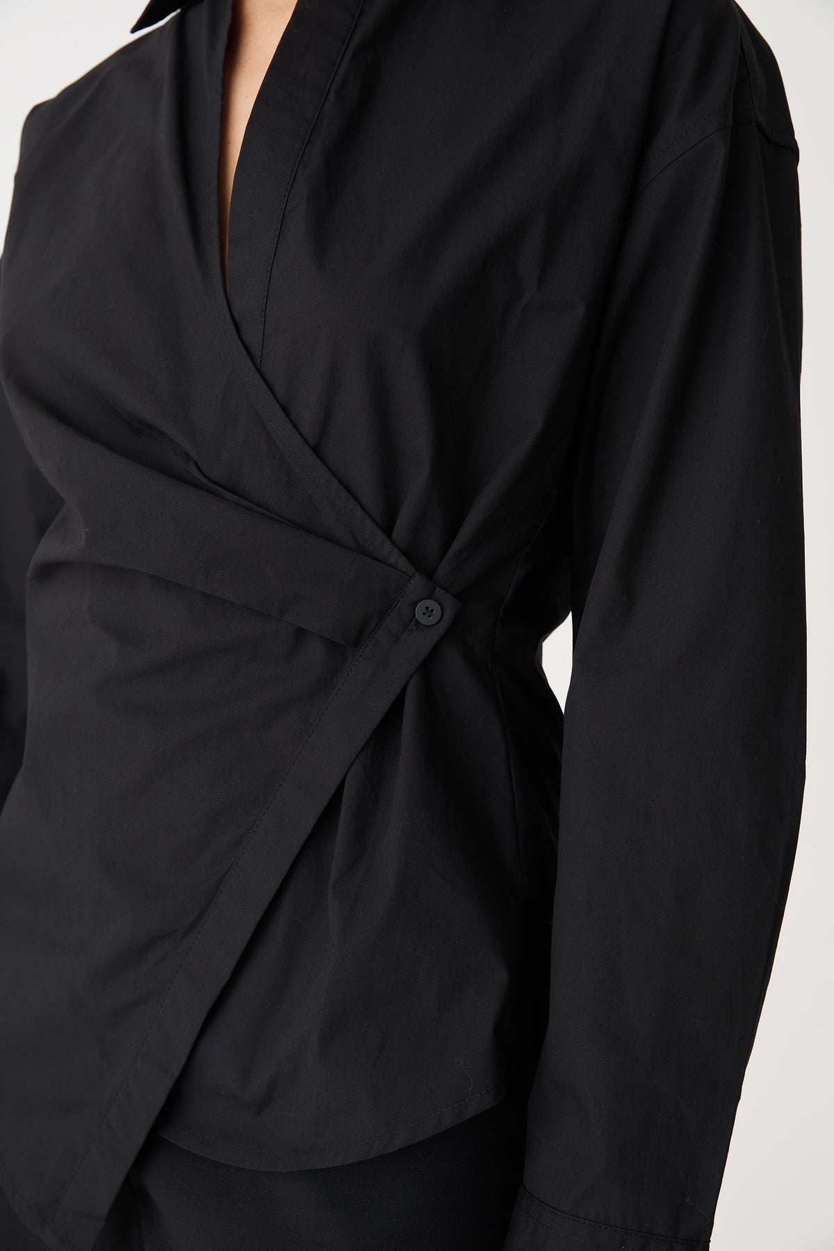 Close-up of the wrap front and single side-button closure in black