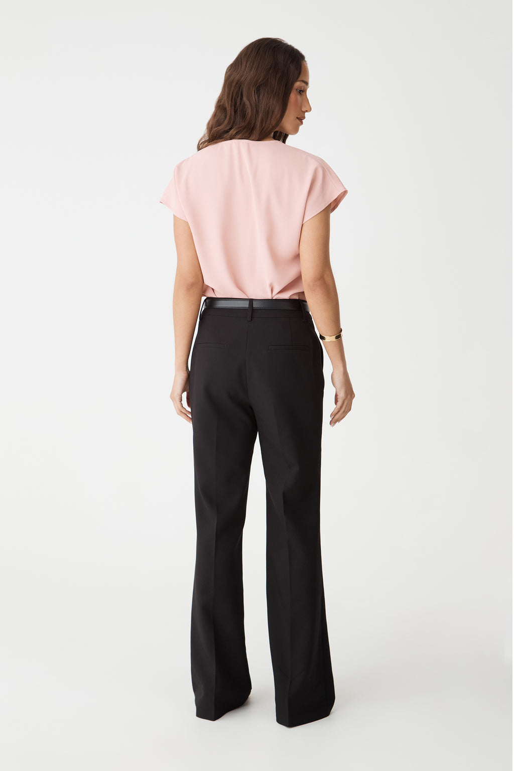 Back view of the Pink Sand top, worn with black wide-leg trousers and belt