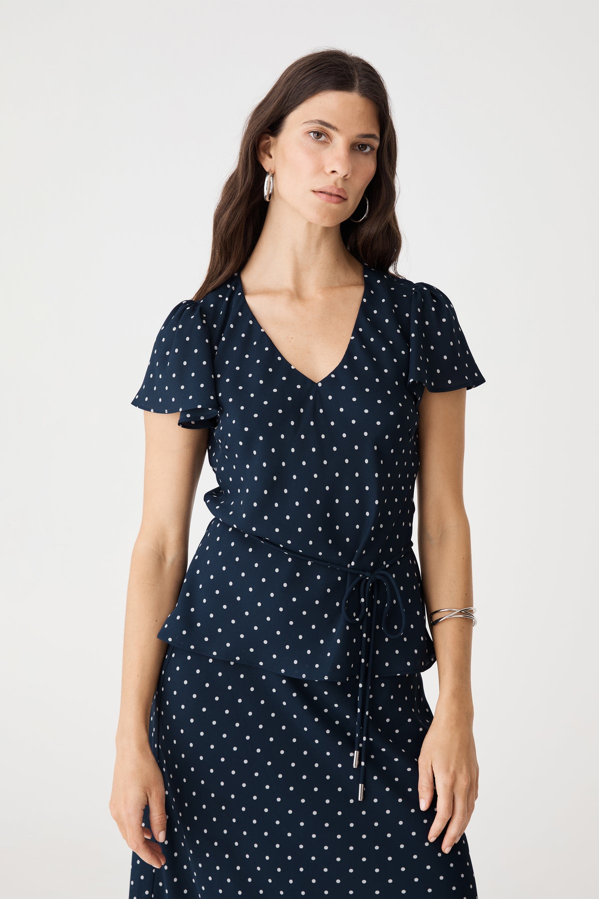 Close-up front view of the V-neckline, white polka dot print and short frill sleeves