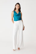 Aurelia Satin Cowl Neck Top in teal, front view, sleeveless with draped cowl neck, worn with white wide-leg trousers