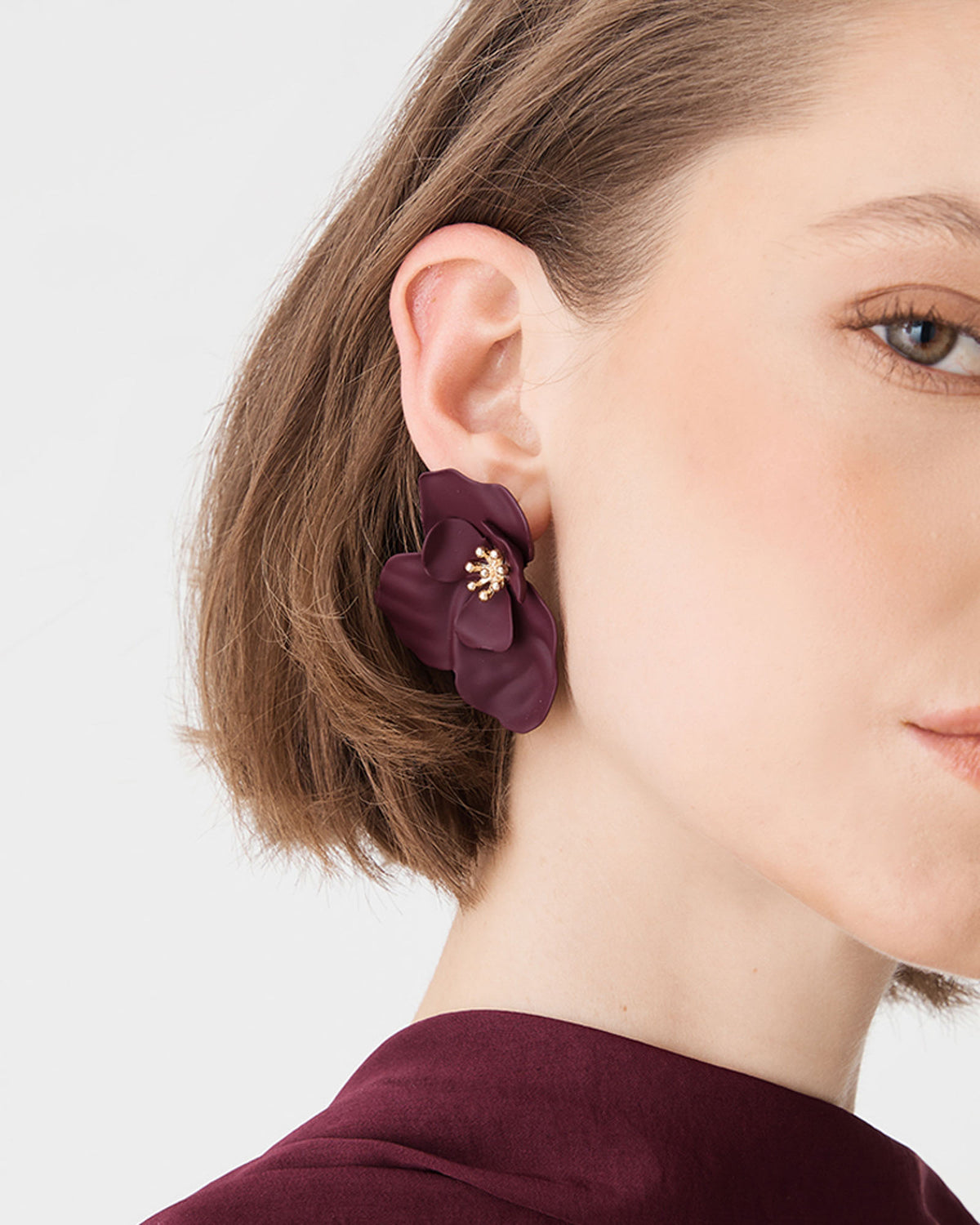 Side view of the burgundy floral stud earring worn with short hair