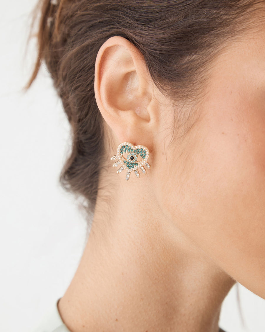 Betty Heart Eye Earrings in gold tone with turquoise inlay and crystals, close-up on ear