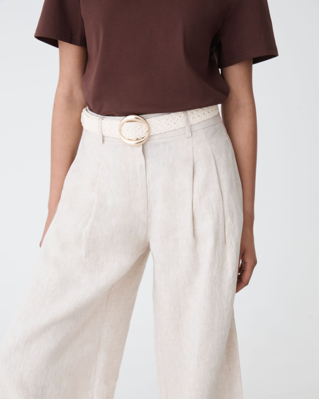 Elena Crochet Belt in ivory with round gold-tone buckle, worn at the waist with linen trousers and brown tee