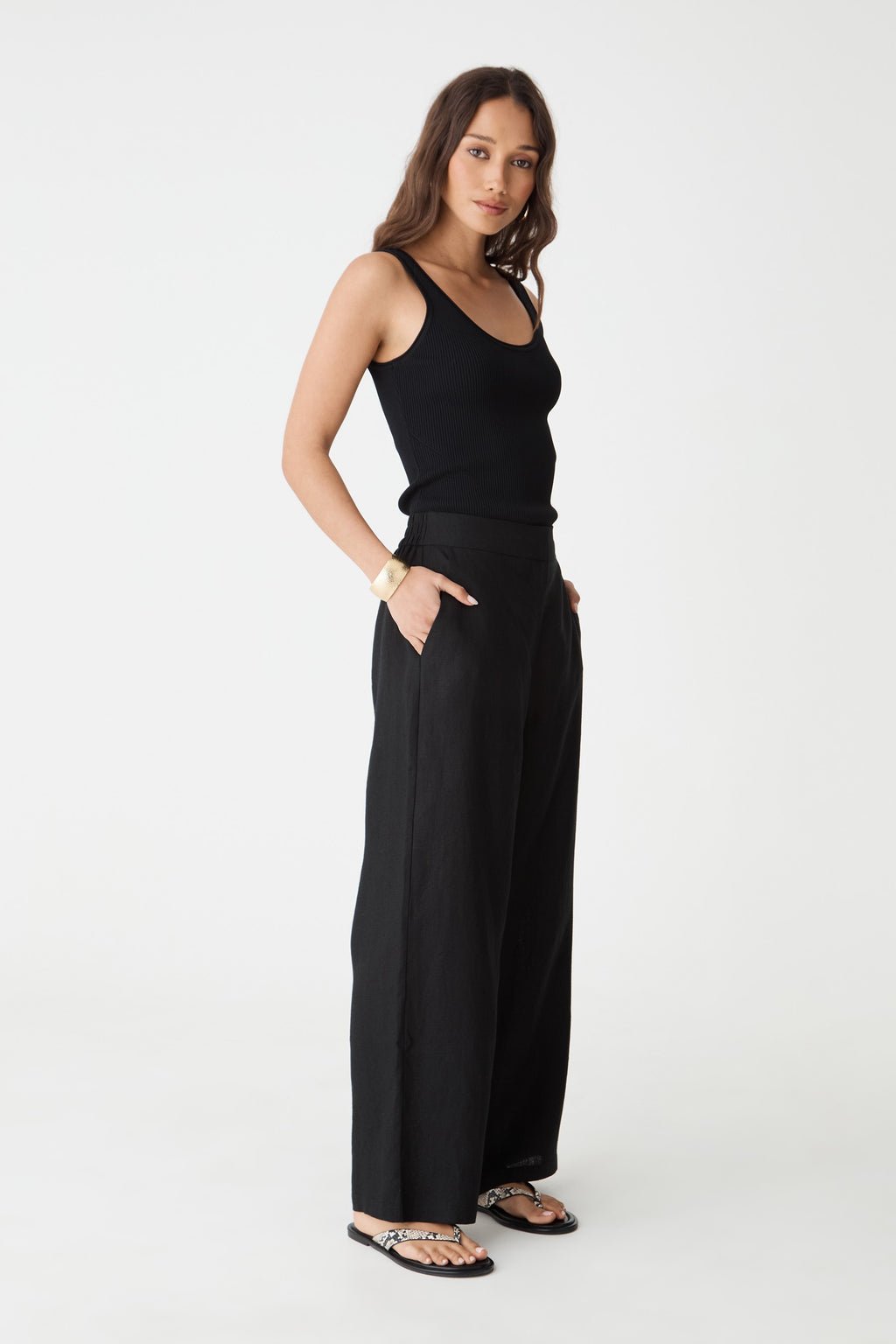 Side view of the black Ami Linen Elastic Back Pants, hand in pocket