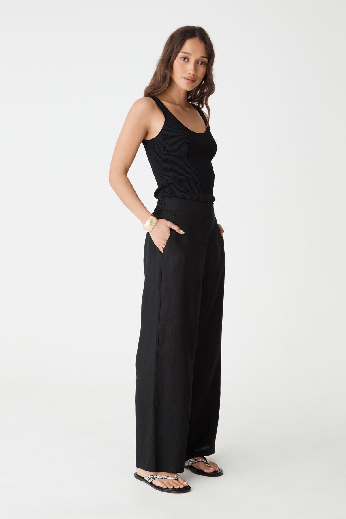 Side view of the black Ami Linen Elastic Back Pants, hand in pocket